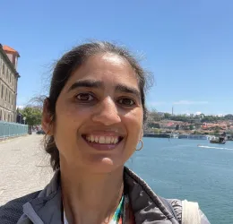 A woman in a gray jacket, with an ocean in the background