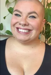 A woman with a dark shirt and a plant in the background