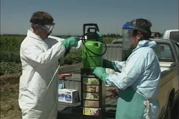 two people in PPE prepare a pesticide sprayer