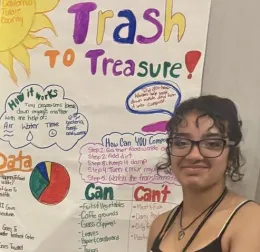 A 4-H youth stands in front of a Trash to Treasure poster highlighting composting efforts in Tulare County.
