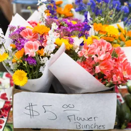 flower bouquets wrapped in paper; a sign reads $5 bouquets