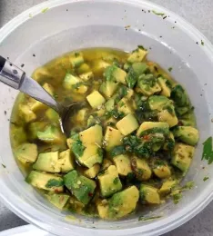 chunks of avocado with dressing in a white bowl