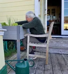 A woman sitting in a chair tending to her raised bed garden