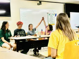 a group of kids sitting at a table during a 4-H club meeting electing a new club officer position
