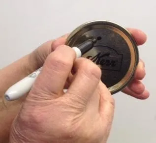 Marcar las tapaderas una vez que las ha usado, es una forma fácil de mantenerlas separadas de las nuevas. (Fotografía: Programa Maestro para Conservar Alimentos de UC)