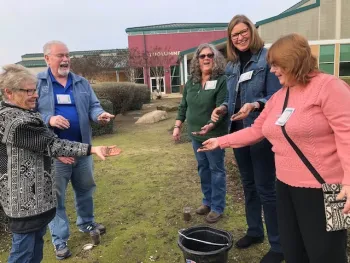 Five smiling gardeners with hands full of soil.