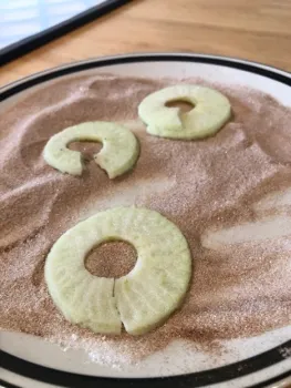 Apple slices on top of cinnamon and sugar