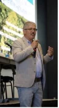 Joshua stands in front of a PowerPoint slide speaking into a mic