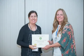 Joy, left, accepts certificate from a woman