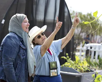 Staff member from a Research and Extension Center (REC) speaking with a visitor in an outdoor setting