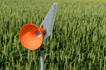 Orange funnel and white fin labeled Spornado on post in crop field