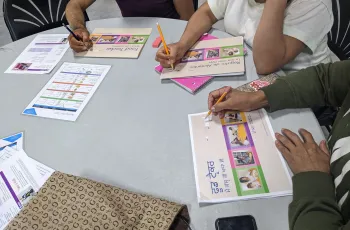 Participants completing enrollment forms in different languages.
