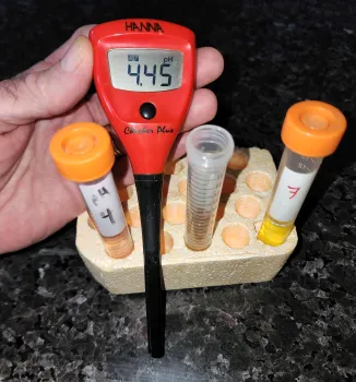 Digital pen-type pH meter flanked by vials of calibration solutions