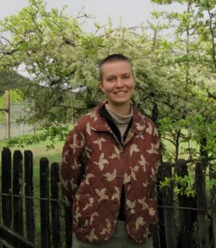 Evelyn George, GrizzlyCorps Fellow at Hopland REC standing by trees and smiling.