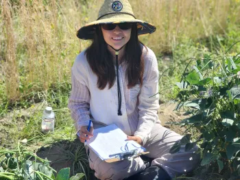 Ana sitting in field with sun hat
