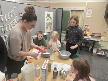 4-H youth and leader around a table filled with slime-making supplies