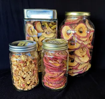 four jars containing dehydrated apples