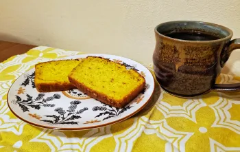 two slices of lemon cake on a dish alongside a cup of coffee