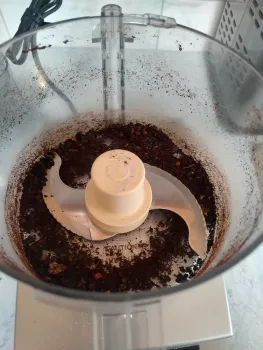 inside the bowl of a food processor, the blade and finely ground dehydrated peppers