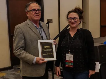 Kassim Al Khatib holds his award. Whitney Brim-DeForest stands beside him
