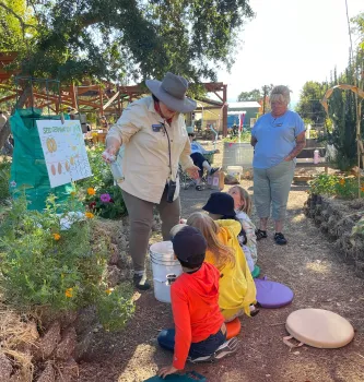 Two adults teaching four children about seed germination