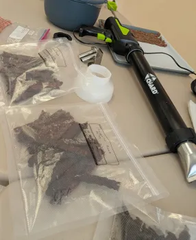 Tool for making beef jerky and samples of jerky on a table