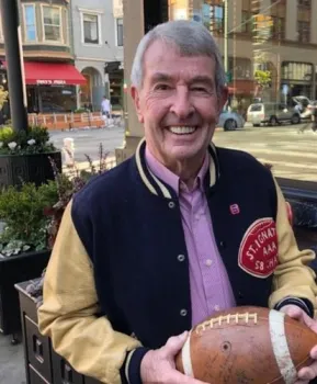 Bob Mullen wearing a St. Ignatius letterman's jacket and holding a football