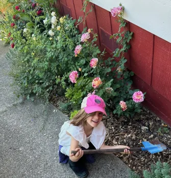 child digging in a garden bed with a child-sized shovel