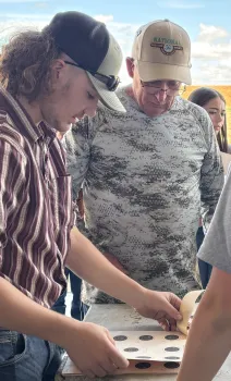 A 4-H volunteer helps a youth check their score sheet at a rifle match.