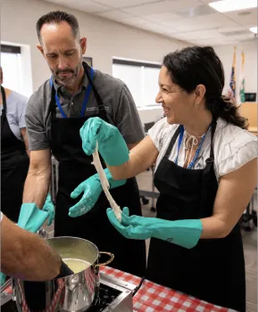 Woman on right smiles as she stretches her cheese. Guy next to her looks down, like maybe he dropped his cheese
