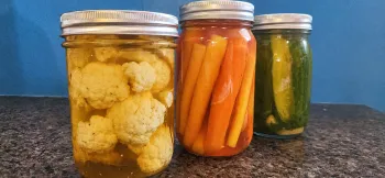 three jars containing pickled vegetables