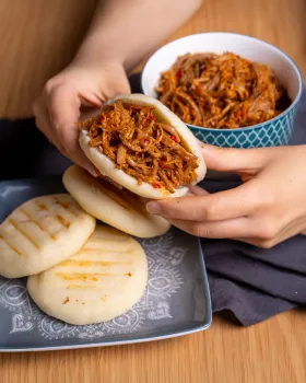 Someone holding an empanadilla venezolana filled with meat.