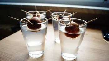 Avocado seeds being held up by toothpicks in a glass full of water.
