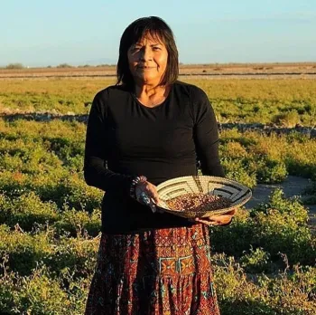 Southwest Regional Food Business Center client standing with a woven basket holding seeds.