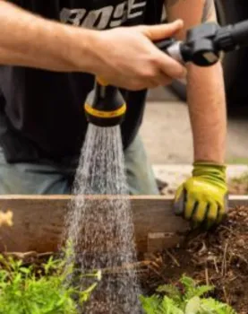 person watering plants with a spray hose nozzle