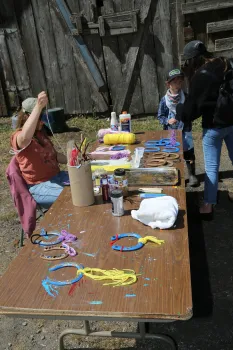 Three people around a table decorate blue horseshoes with colored yarn
