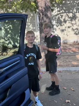 two boys look into an open car door as they go to school