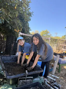 two youth mixing soil in a tub
