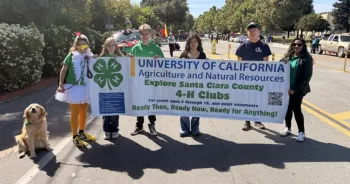 4-H youth marching in a parade holding a 4-H banner