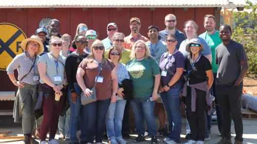 A group of people pose for a photo in several rows during a farm tour