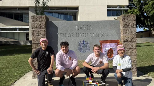 Almond Robotics, Modular Learning, Inc. team crouch by the Davis Senior High School sign