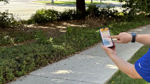 Disembodied hand points to flame image on a California map on a phone
