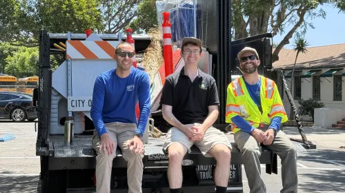 Jason Scott-Sheets, middle, sits with two Public Works colleagues at the back of a truck filled with tools and signs during a community cleanup event