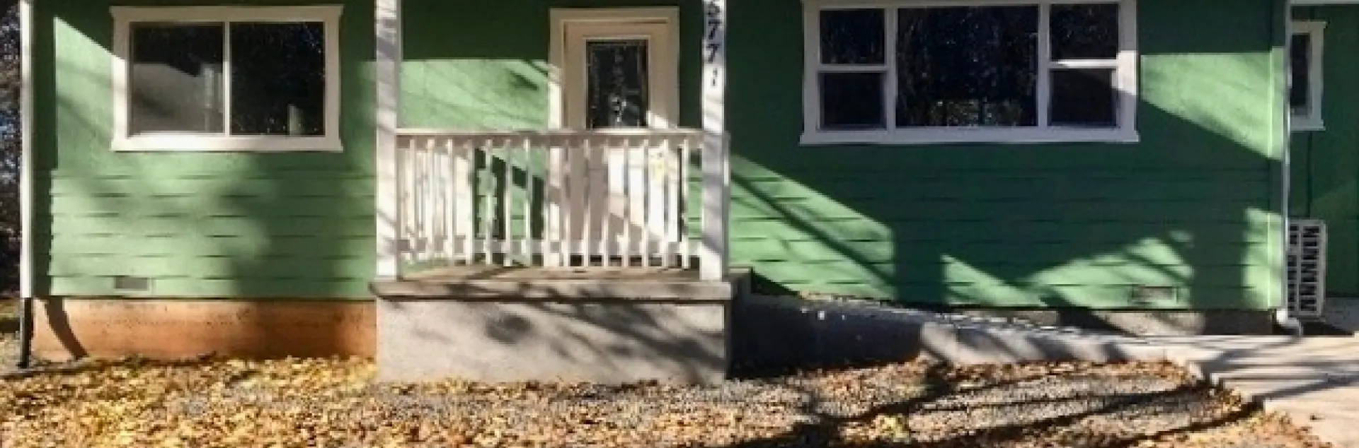 Casa de madera color verde con detalles blancos.