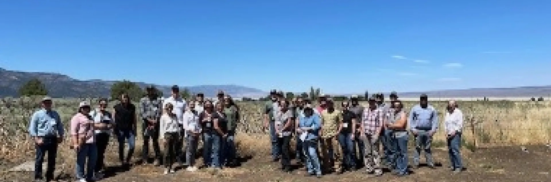 A group photo in open space under a blue sky.