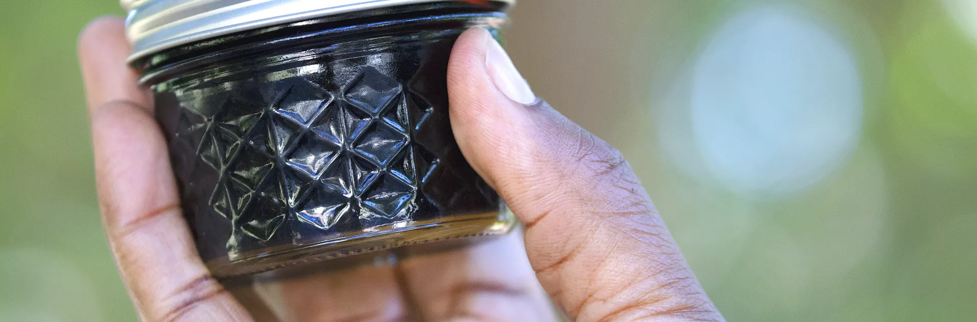 Hand holding a jar of elderberry ja