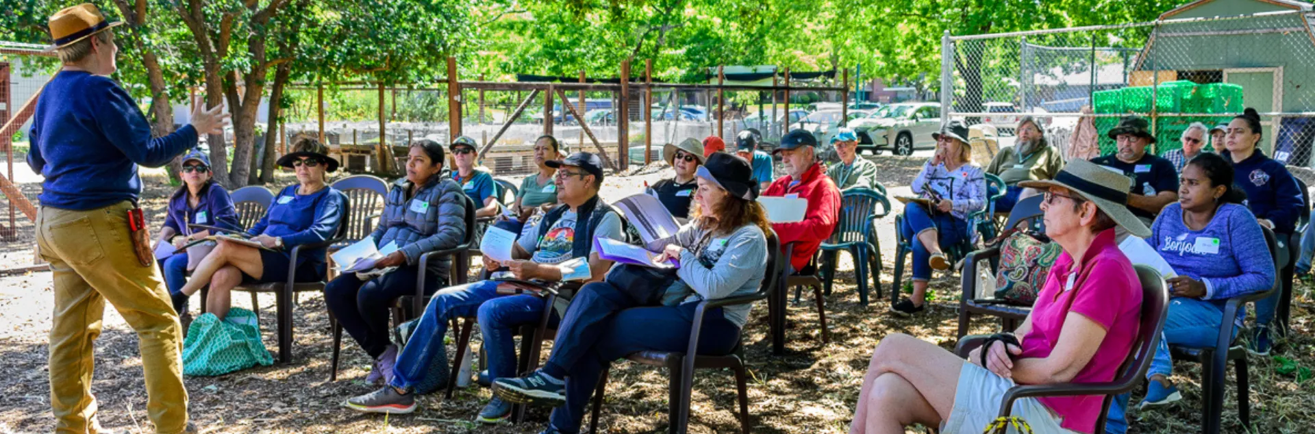 UC Master Gardener standing in a garden setting giving a talk to people sitting in chairs. 