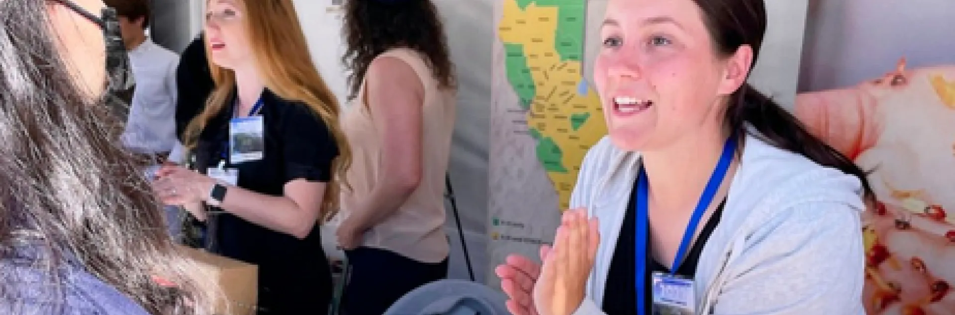 A woman speaks to someone visiting an event booth. Text: GivingTuesday