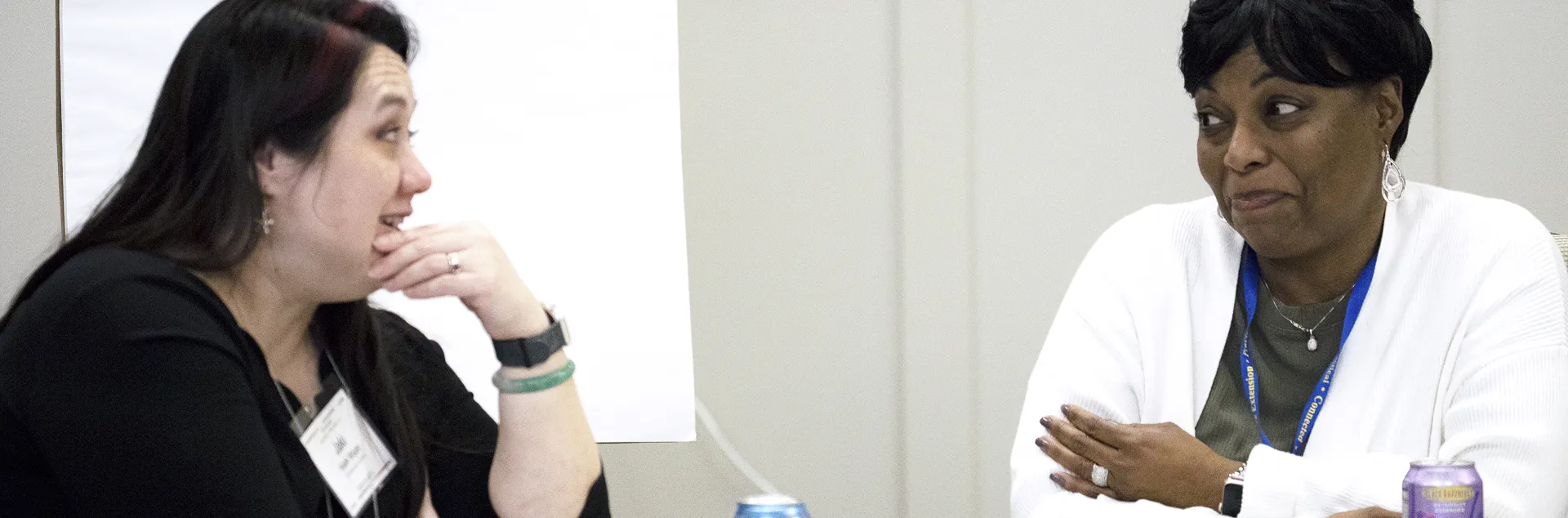 Jaki Hsieh Wojan and Tina Jordan sit at a table having a ocnversation.