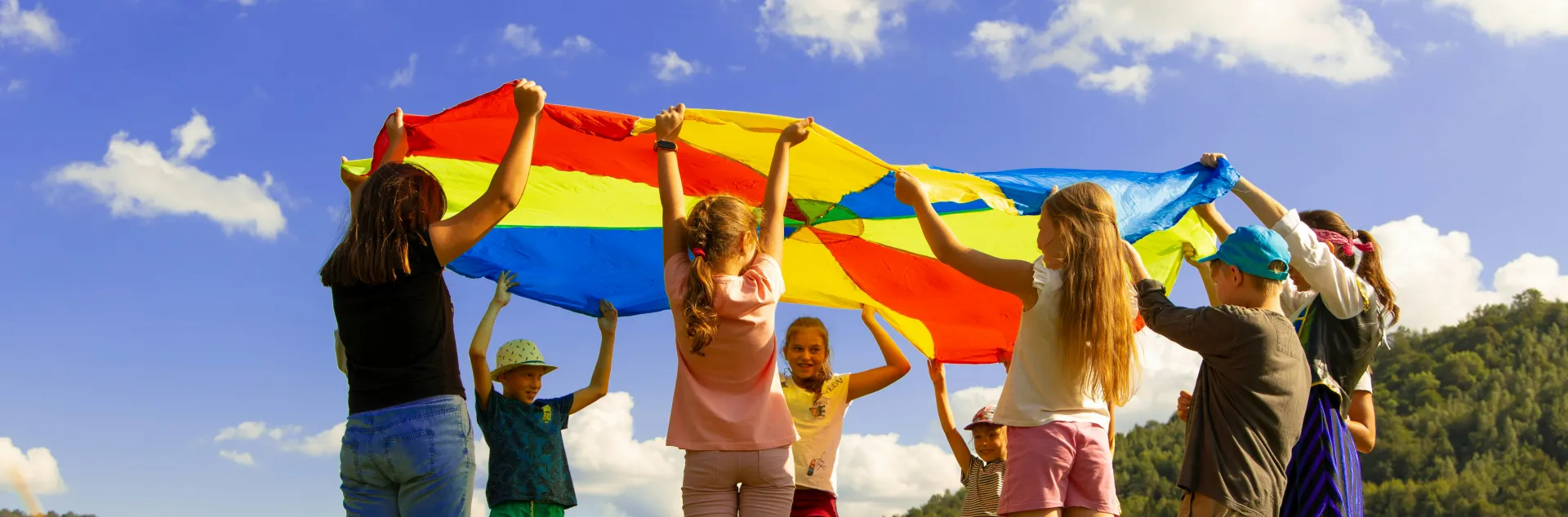 A group of children play outside with a parachute